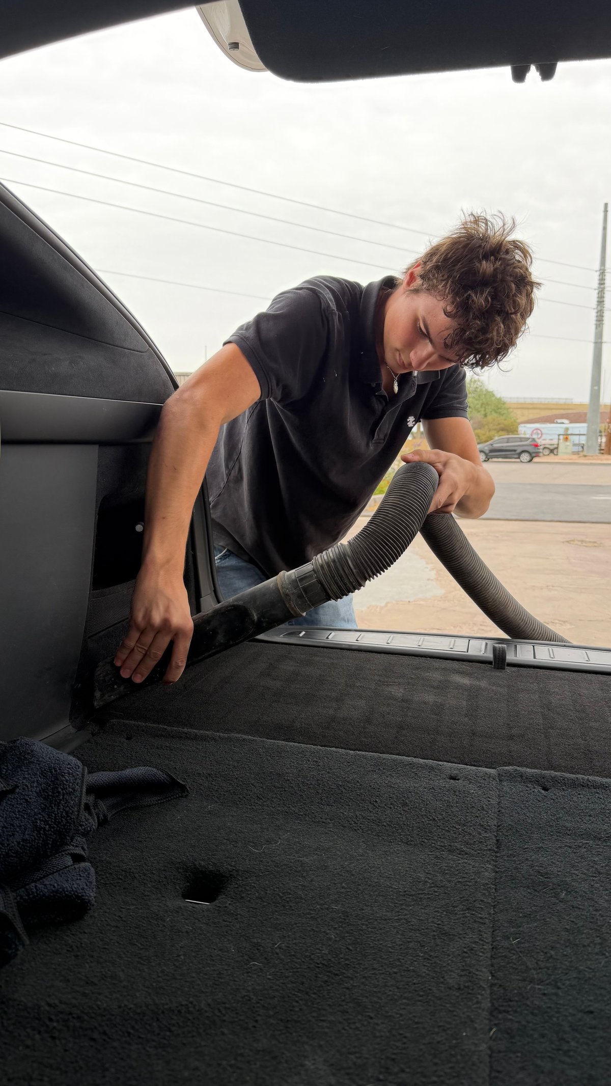 Man in black shirt cleaning interior of truck bed with vacuum hose