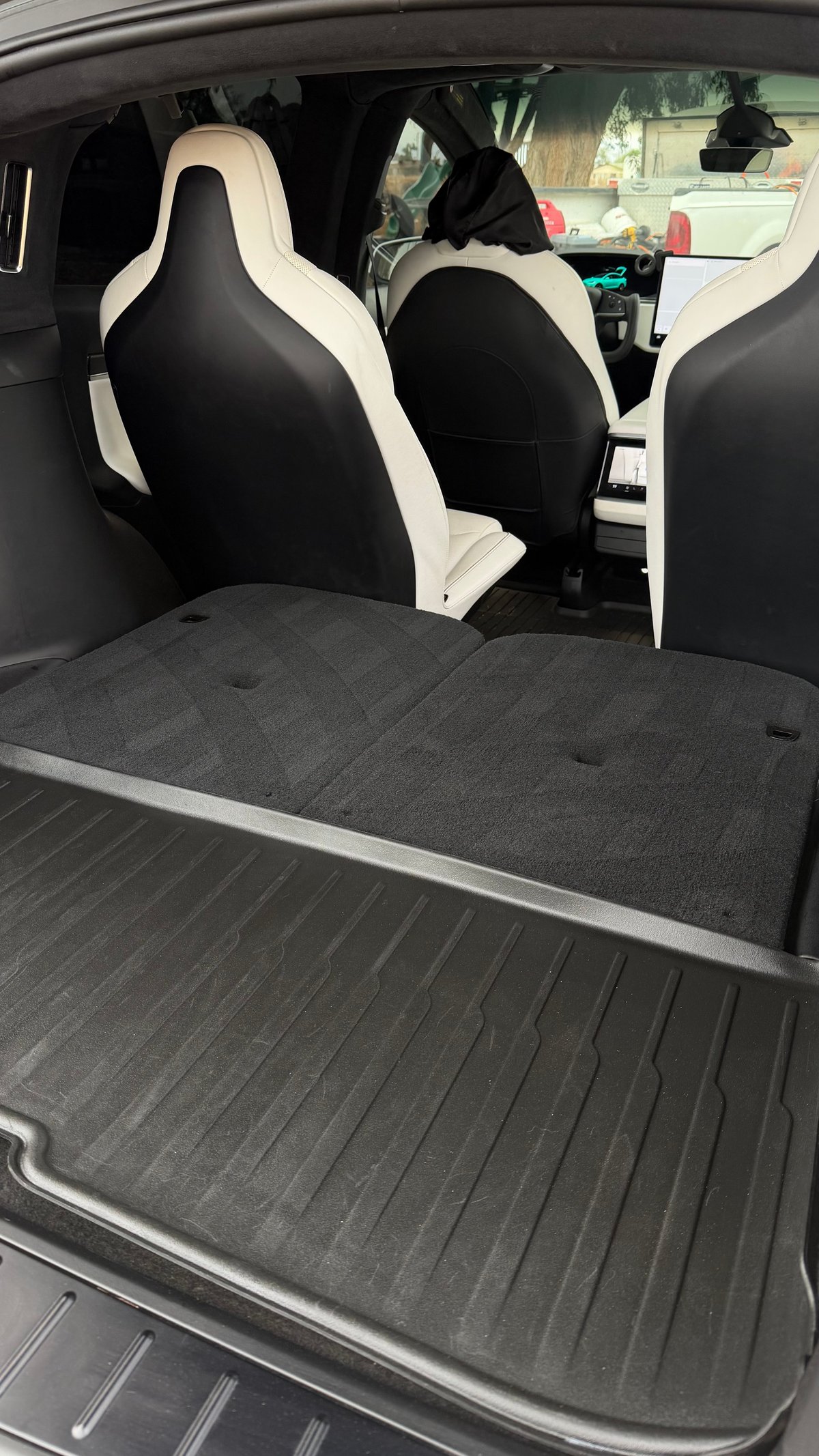 Interior of a car with open trunk showing black and white sporty bucket seats and gray rubber cargo mat